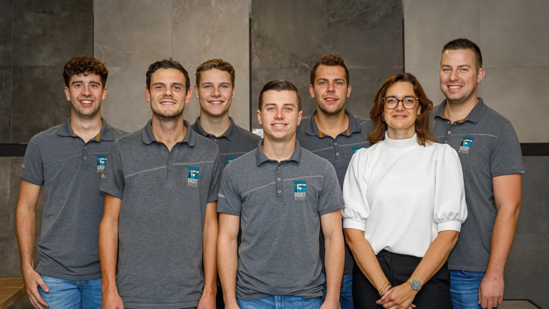 Een sfeervolle groepsfoto van het voltallige personeel van tegelbedrijf Groot in tegels, waarop het vakkundige en enthousiaste team vol trots en met een lach samen poseert.