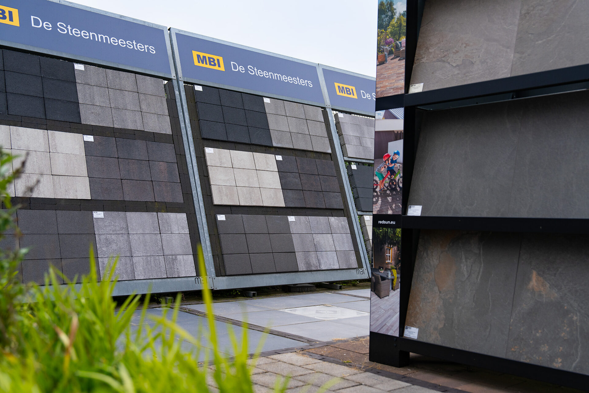 Grote presentatierekken met diverse soorten sierbestrating en grote terrastegels op het showterrein van Groot in Tegels.