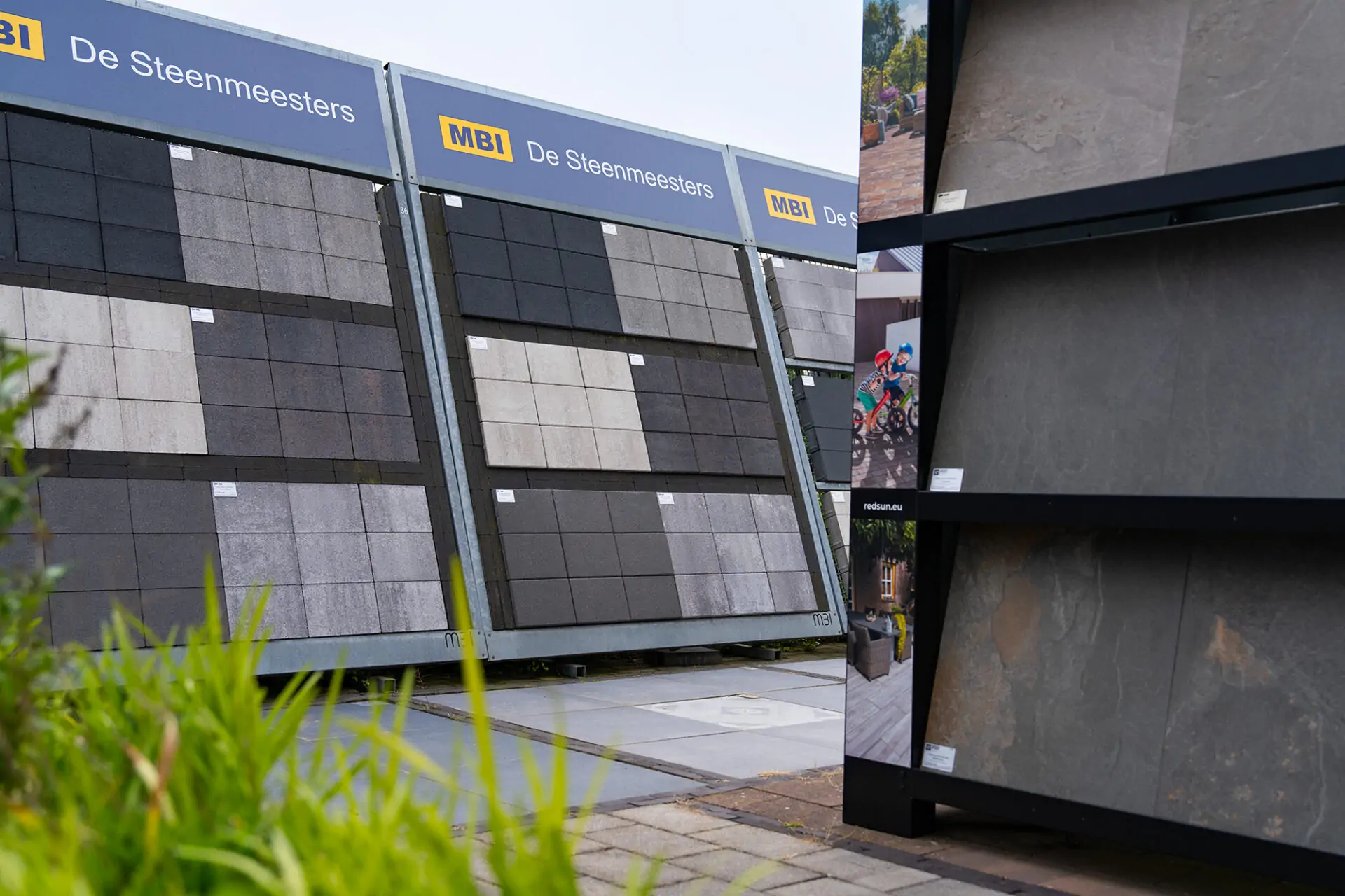 Grote presentatierekken met diverse soorten sierbestrating en grote terrastegels op het showterrein van Groot in Tegels.